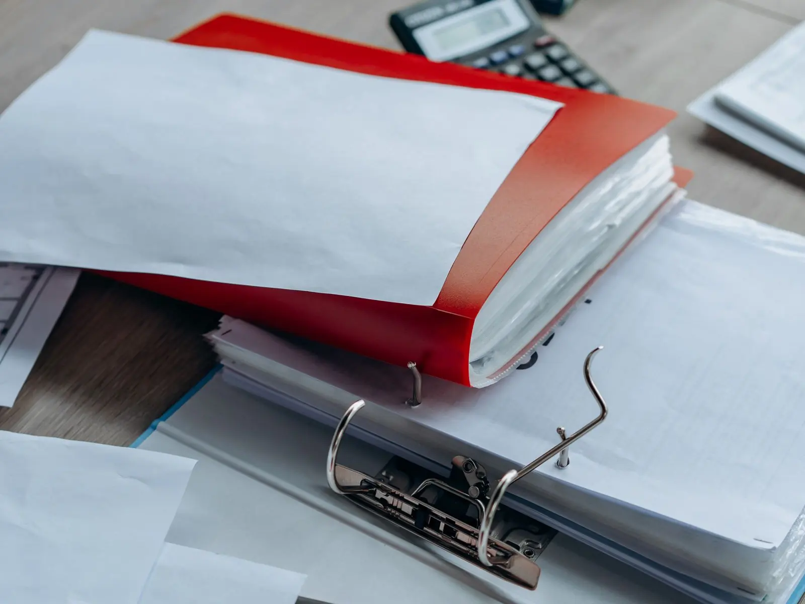 Archivadores abiertos con documentación y una calculadora encima de la mesa