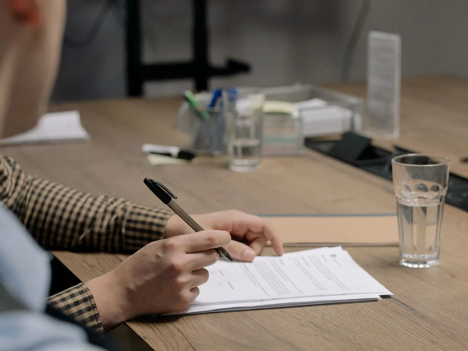 Una persona firmando un documento en la mesa de un despacho